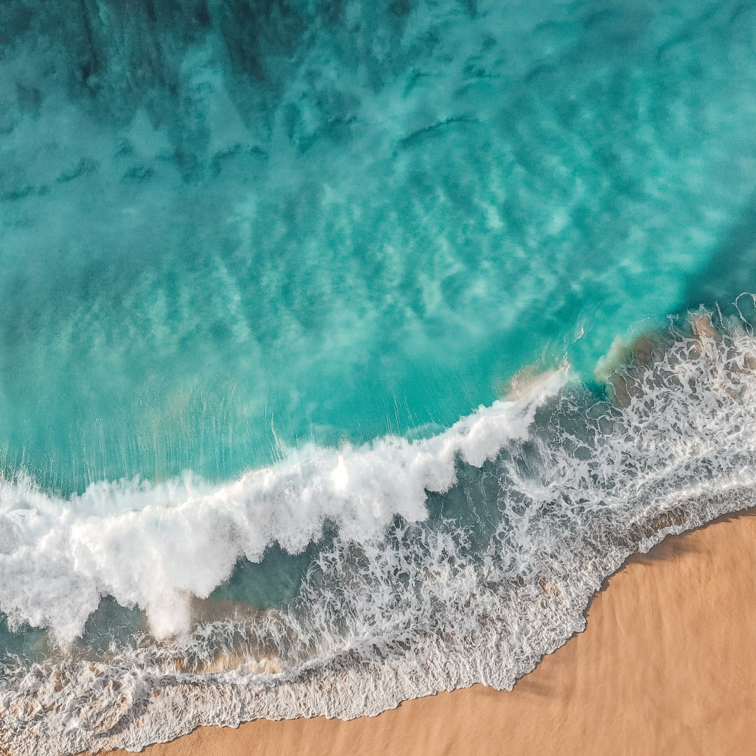 Crystal-clear ocean wave rolling onto a sandy beach, representing the natural purity of boric acid's origins.