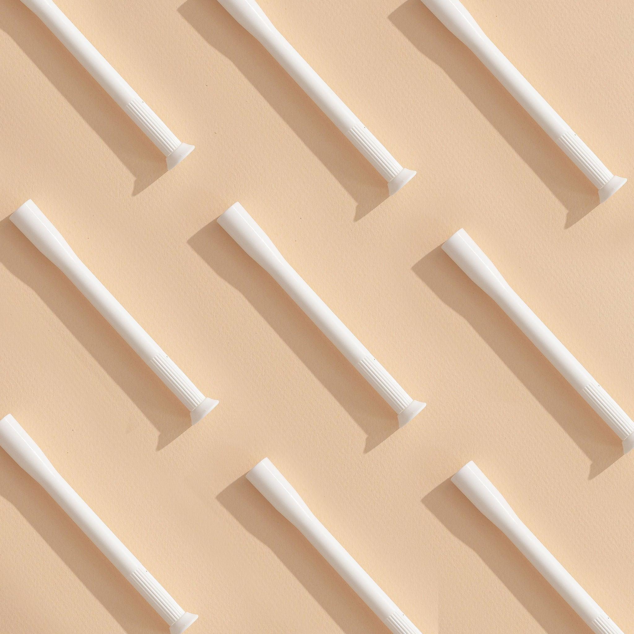 A flat lay image of several vaginal suppository applicators on a neutral background. 