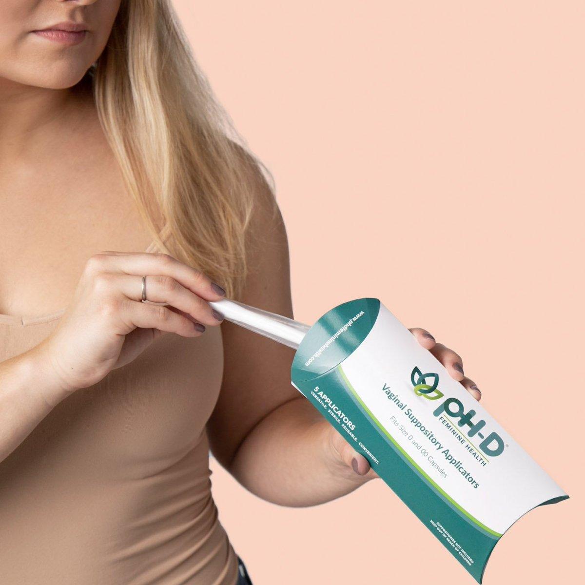 A woman pulling out a pH-D Feminine Health Vaginal Suppository Applicator from the box. 